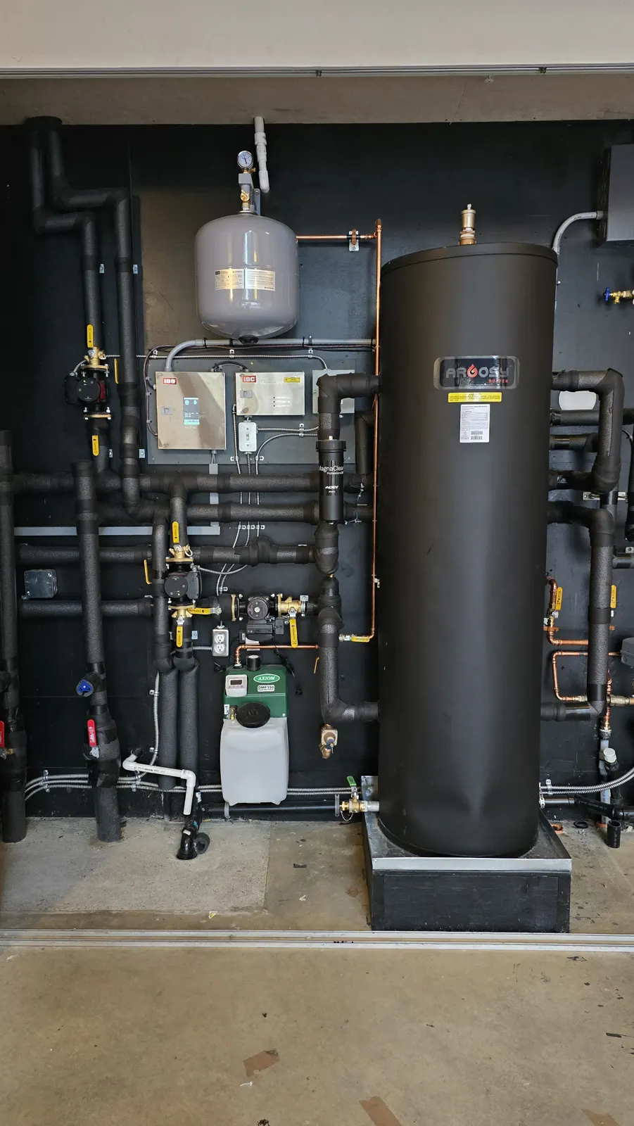 After: black mechanical wall with Argosy buffer tank, expansion tank, IBC controls and condensate neutralizer