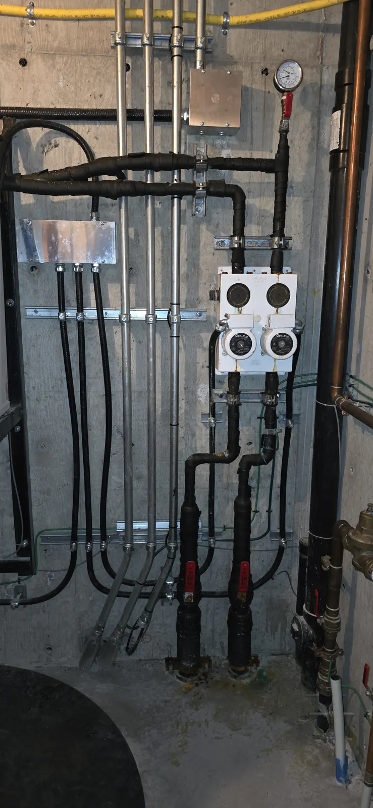 Before: older piping and fittings on the concrete wall