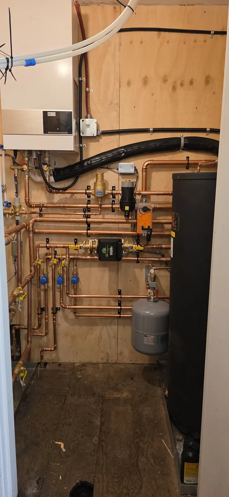 After: Midea hydro box on a plywood panel with copper manifold, zone valves, buffer tank and expansion tank