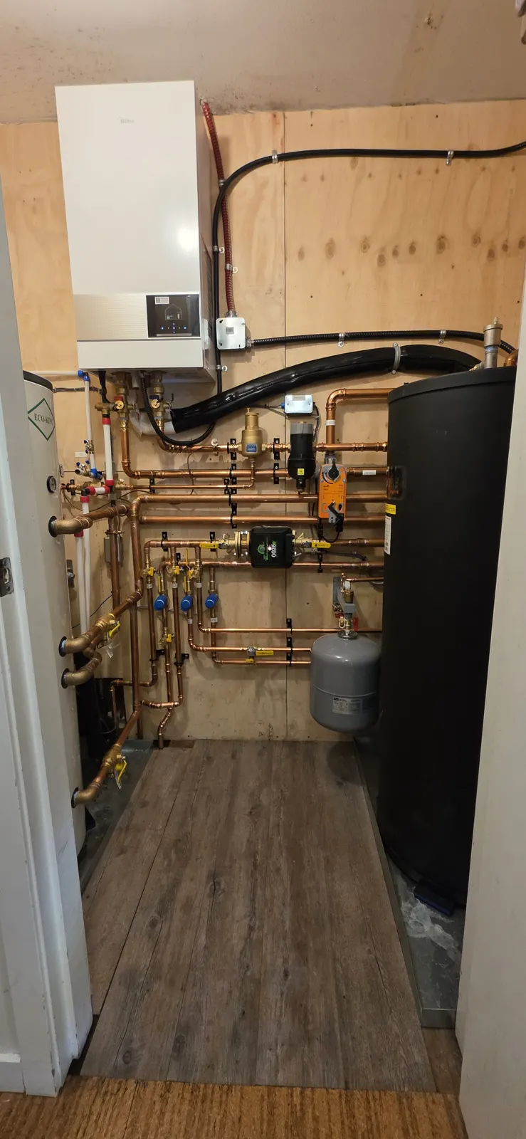 Midea hydro box on plywood with a copper manifold, zone valves, buffer tank and expansion tank
