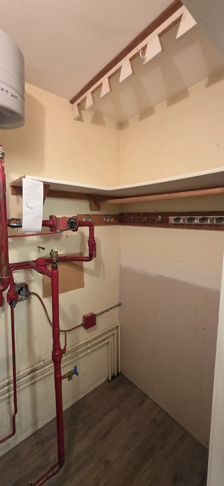 Before: red-painted piping and the old expansion tank in the closet