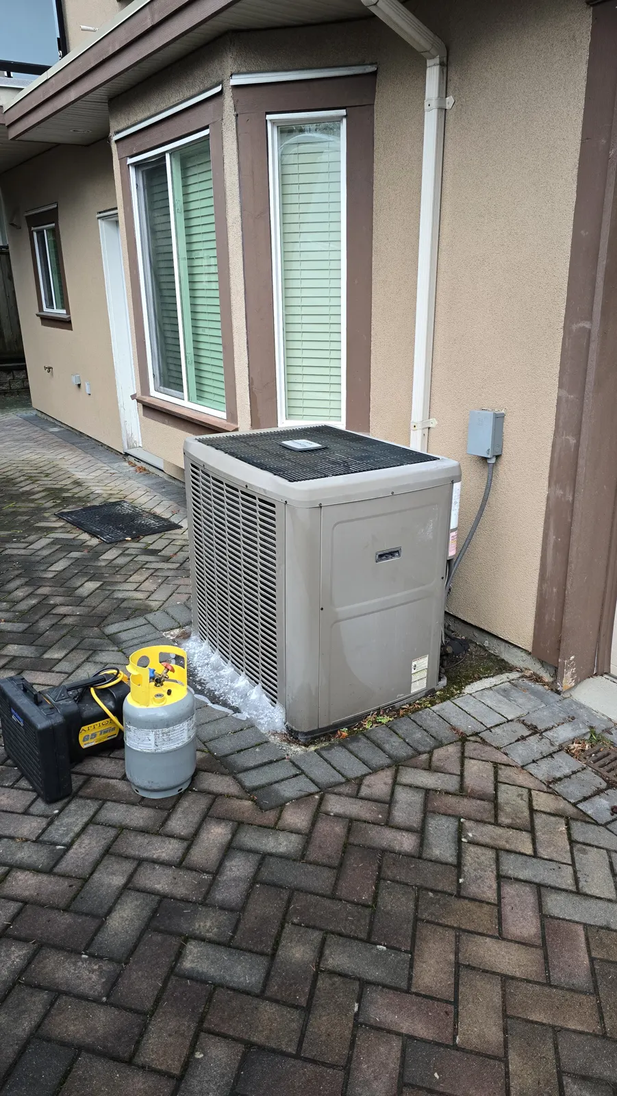 Before: iced-up York outdoor unit beside a stucco house, with a refrigerant recovery machine and cylinder